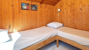 A wooden cabin room with two bunk beds, wooden walls, and a sloped ceiling.