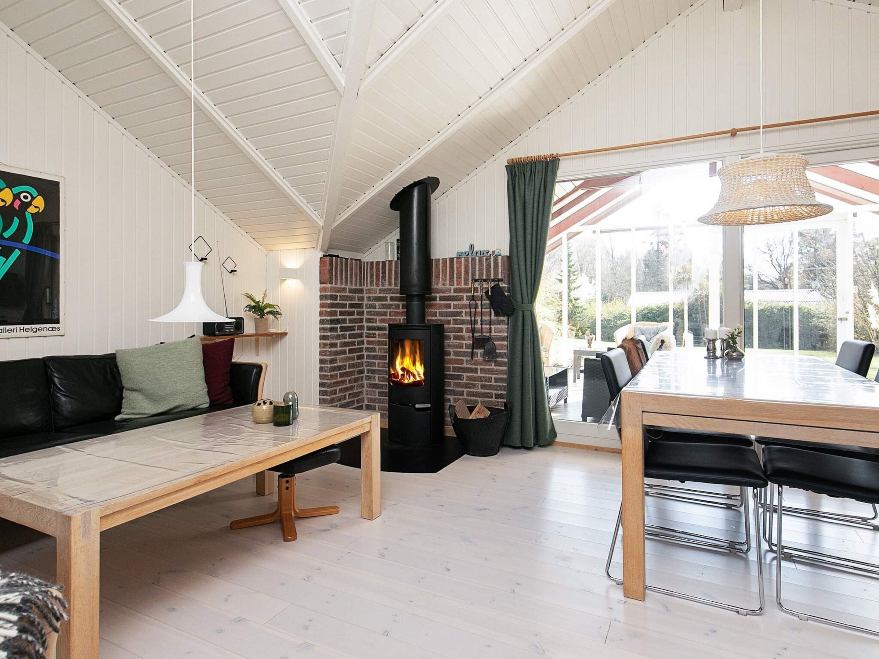 Un interior acogedor con chimenea, un comedor y vistas amplias a través de grandes ventanas.