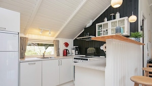 A modern kitchen with white cabinets, a central island, a stove, and a coffee maker.