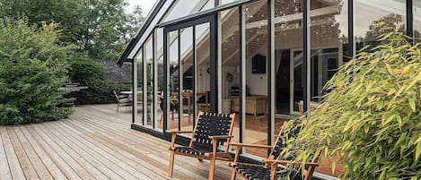A wooden deck with two chairs and a glass-enclosed structure.