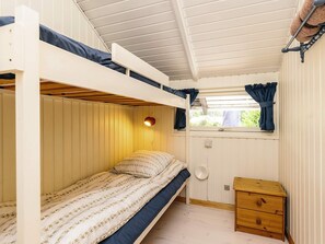 Dormitorio con literas, ventana, lámpara de noche y cómoda de madera.