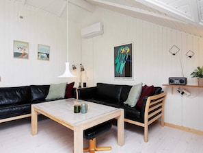 A modern living room with a black leather sofa, a wooden coffee table, and a white pendant light. - 6 Person Holiday Home in Humble (Sydlangeland)