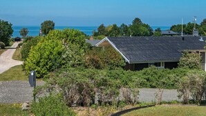 A coastal property with a gravel driveway leading to a house with a dark roof, surrounded by lush greenery and a view of the sea. - 6 Person Holiday Home in Allingabro-by Traum (Allingåbro)