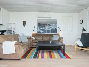 A living room with a brown sofa, a black coffee table, and a colorful striped rug.