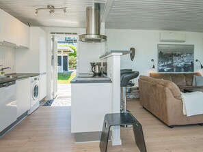 A modern kitchen with a central island, a dining area with a sofa, and a view of the outdoors.