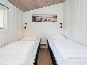 A room with two single beds, a small table, and a wall-mounted picture.
