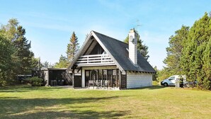 A small, single-story building with a sloped roof and a chimney, surrounded by a grassy lawn and trees. - Classic Holiday Home in Hals near Sea (Hals)