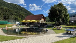 A lakeside building with outdoor seating and a swimming area.