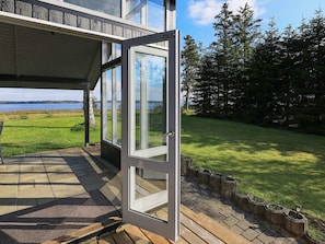 A modern house with a large glass door leading to a covered porch. - 4 Person Holiday Home in Hojslev (Hojslev)