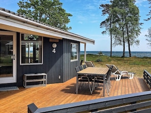 A wooden deck with a table and chairs, a small outdoor seating area, and a view of the sea. - 4 Star Holiday Home in Nexo (Nexø)