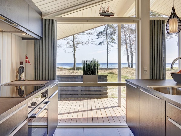 A modern kitchen with a view of the beach and ocean.