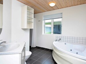 A bathroom with a bathtub, toilet, sink, and a window with a view.