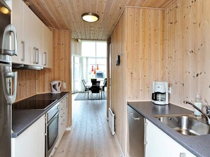 A modern kitchen with wooden paneling, stainless steel appliances, and a dining area with a view.