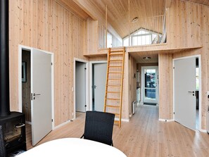 Quarto com paredes de madeira, um mezanino e uma escada para o mezanino.