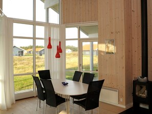 A dining area with a table and chairs, large windows, and a wood-paneled wall.