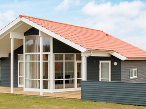 A modern house with a sloped roof, large windows, and a wooden deck.