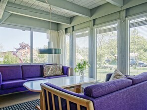 A room with a purple sofa, a round table, and a hanging light fixture. - 8 Person Holiday Home in Allinge (Allinge)