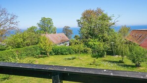 A coastal property with a view of the sea, surrounded by greenery and traditional architecture.