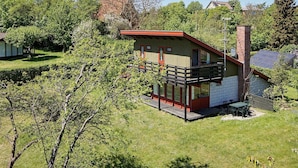 A single-story house with a balcony, surrounded by trees and a clear sky. - 8 Person Holiday Home in Allinge (Allinge)
