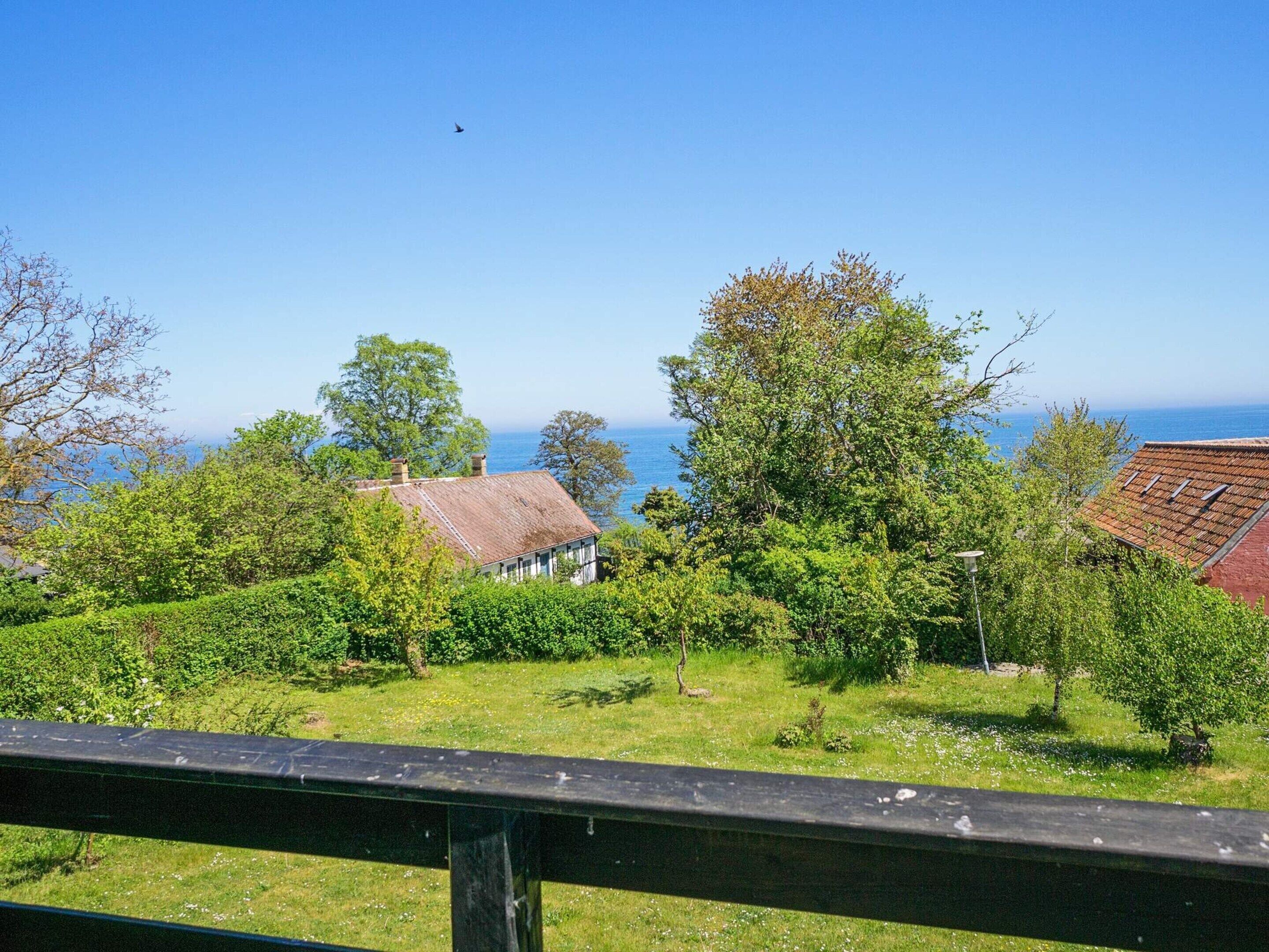 A coastal view with a house, trees, and a clear sky.