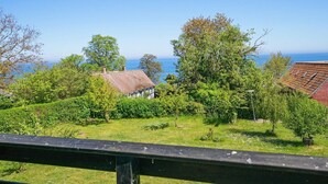 A coastal view with a house, trees, and a clear sky.