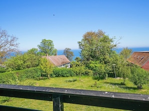 Une vue sur la côte, avec une maison, des arbres et un ciel dégagé.