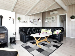 A modern living room with a black leather sofa, a round white table, and a black and white checkered rug. - Sprawling Holiday Home at Hvide Sande With Indoor Whirlpool (Hvide Sande)