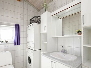 A modern bathroom with a built-in washing machine, a sink with a mirror above it, and a window with a purple curtain. - Sprawling Holiday Home at Hvide Sande With Indoor Whirlpool (Hvide Sande)
