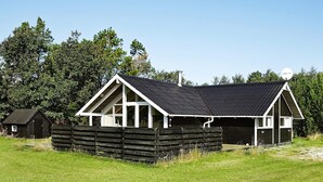 Een laag gebouw met een puntig dak, een overdekte veranda en een omheind terrein.