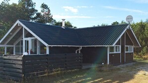 Een gelijkvloers gebouw met een schuin dak, een schotelantenne en een houten terras.