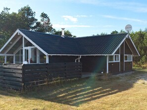 En enplansbyggnad med ett sluttande tak, en satellitantenn och en träveranda.