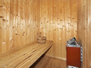 A sauna room with wooden walls and a bench.