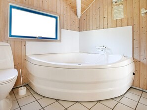 A bathroom with a white bathtub, a toilet, and a window.