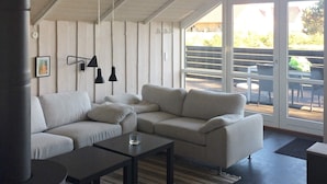 A modern living room with a sectional sofa, a coffee table, and pendant lights.