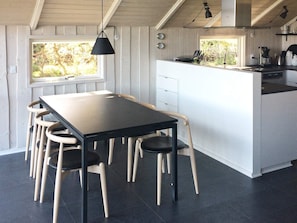 Una cocina moderna con una isla central, un comedor con mesa y sillas, y vistas al exterior.