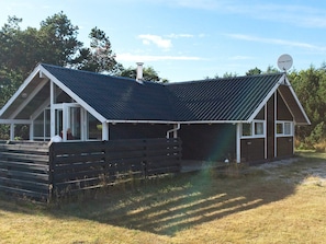 A wooden cabin with a sloped roof and a satellite dish.