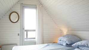Un dormitorio con dos camas, una ventana con cortinas y un espejo en la pared.