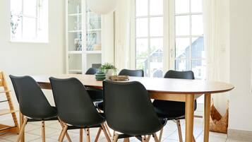 Un comedor con una mesa redonda, seis sillas y una lámpara colgante.