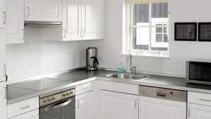 Una cocina moderna con armarios blancos, electrodomésticos de acero inoxidable, horno integrado y lavavajillas.