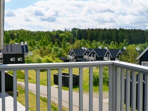 A residential area with multiple houses, a road, and a forested hill in the background.