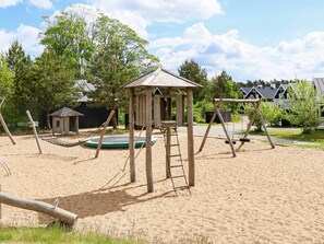 A playground with a swing set, a climbing structure, and a sandbox. - 4 Star Holiday Home in Gjern (Gjern)