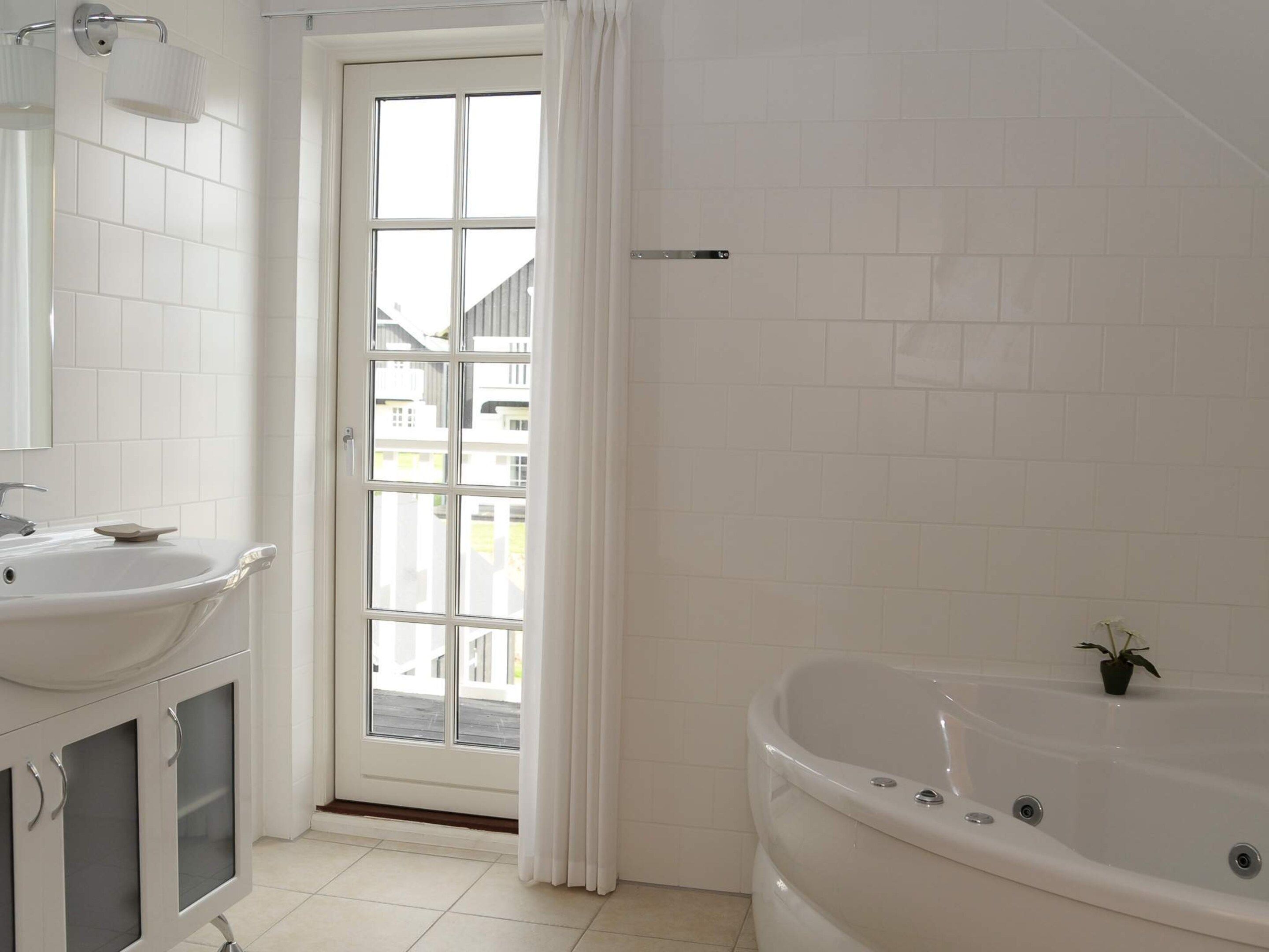Une salle de bain avec un lavabo blanc, un miroir et une baignoire.