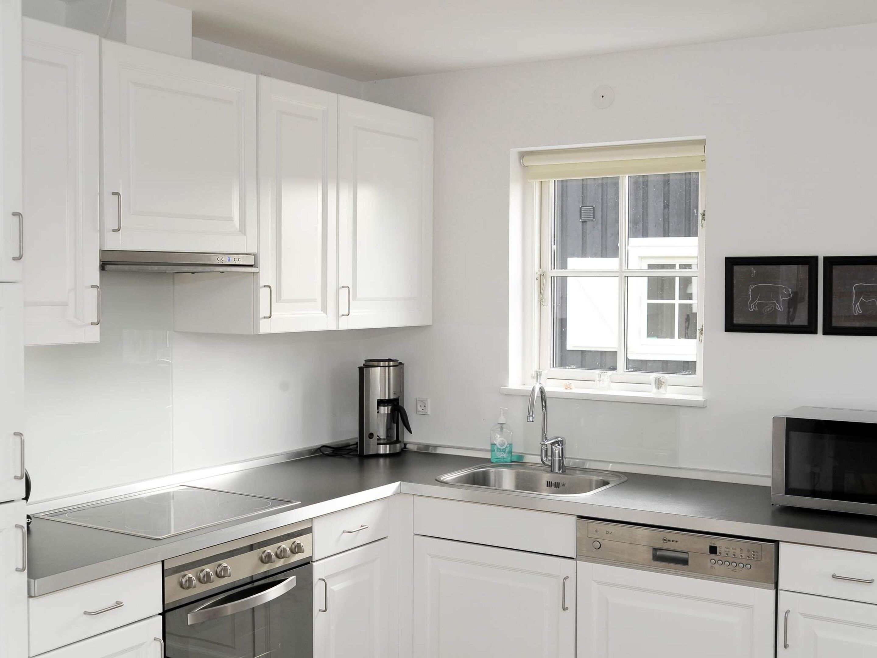 A modern kitchen with white cabinets, stainless steel appliances, a built-in oven, and a dishwasher.