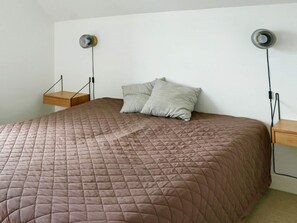 A bedroom with a queen-sized bed, two bedside tables, and two wall-mounted lamps.