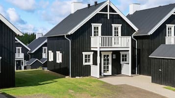 A row of black wooden buildings with white trim, featuring balconies and large windows.