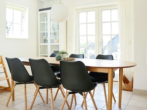 Uma sala de jantar com uma mesa redonda, seis cadeiras e um lustre.