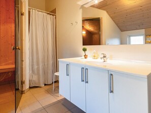 A modern bathroom with a white vanity, a small potted plant, and a shower curtain.
