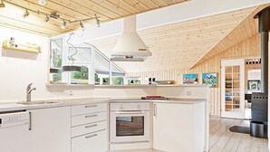 A modern kitchen with white cabinetry, a built-in oven, and a large window overlooking greenery.