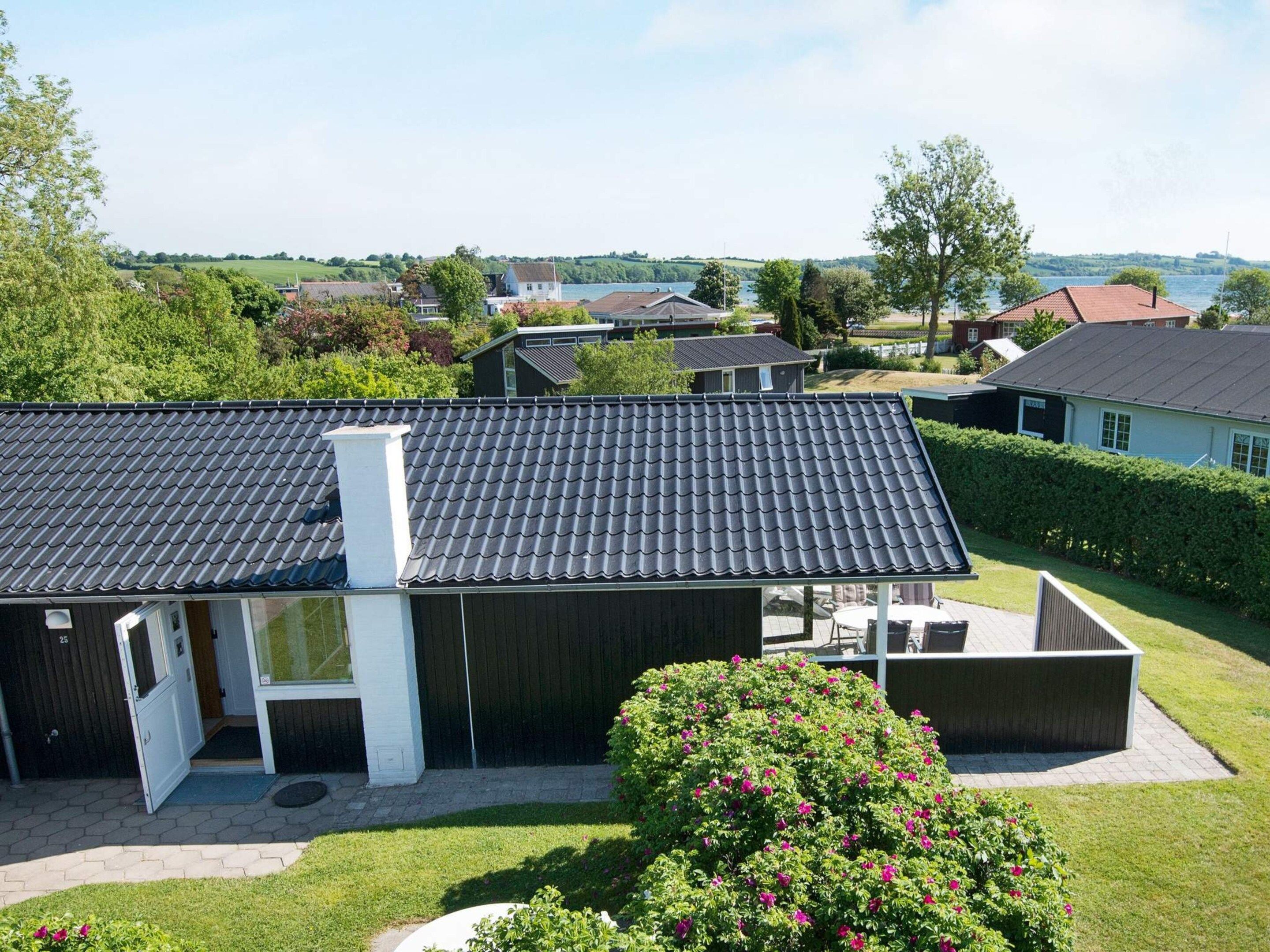 Ein Wohnhaus mit einer großen, offenen Terrasse, einem überdachten Sitzbereich und Blick auf einen See.