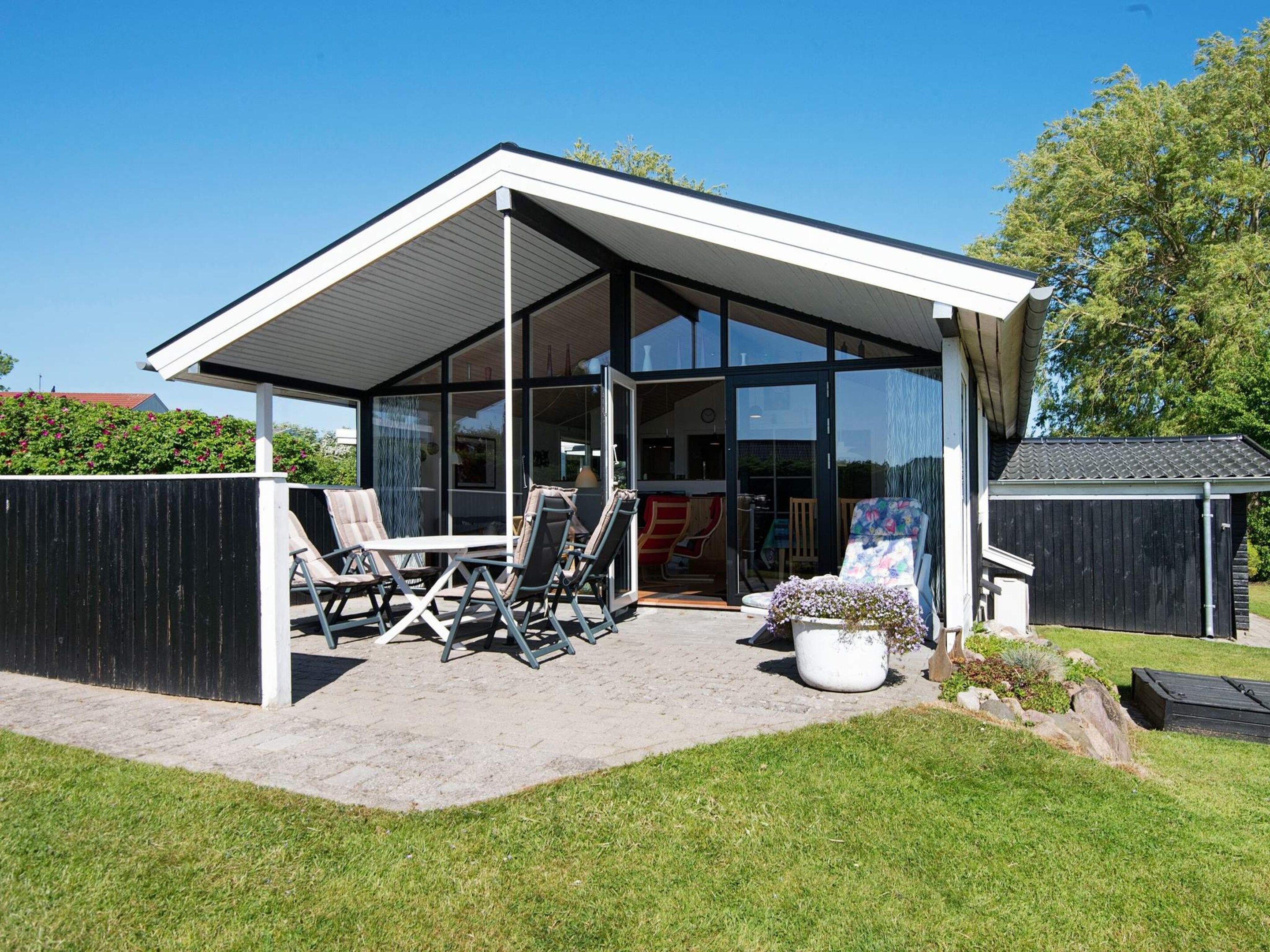 A modern house with a covered patio, outdoor seating, and a glass door leading to the interior.